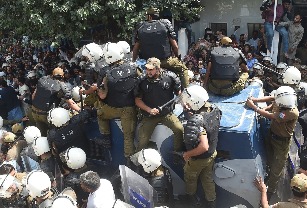 Pakistani policemen sit on armoured vehicle carrying opposition leader Shahbaz Sharif after the corruption court hearing in Lahore on October 6, 2018. (AFP / ARIF ALI)