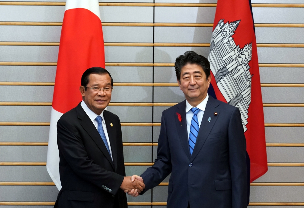 Japanese Prime Minister Shinzo Abe, right, and Cambodia's Prime Minister Hun Sen shake hands prior to their meeting at Abe’s office in Tokyo Monday, Oct. 8, 2018. Eugene Hoshiko/Pool via REUTERS