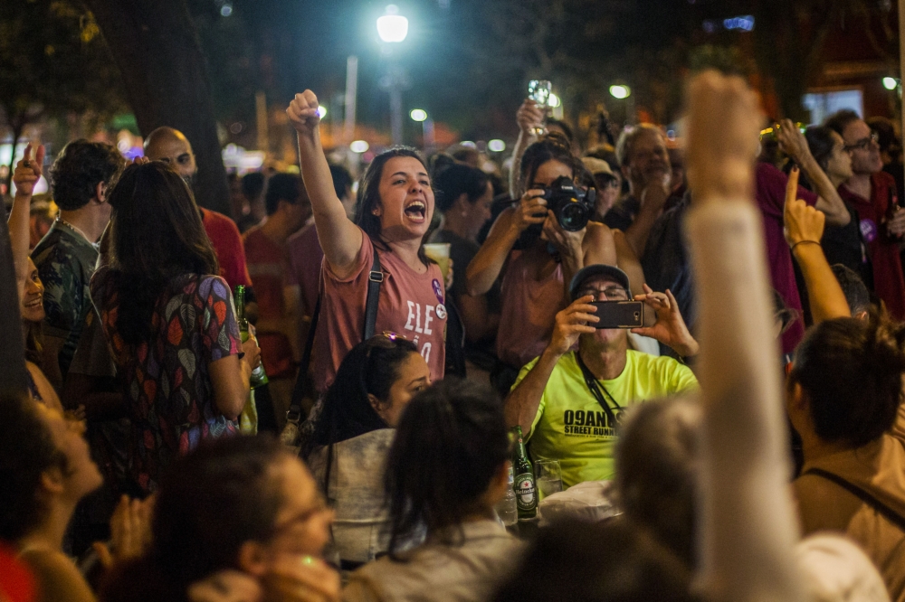 Supporters of Brazilian presidential candidate for the Workers' Party Fernando Haddad, celebrate the result after the vote count at a bar in Sao Salvador square, Laranjeiras neighborhood, in the South Zone of Rio de Janeiro, Brazil, on October 07, 2018.  