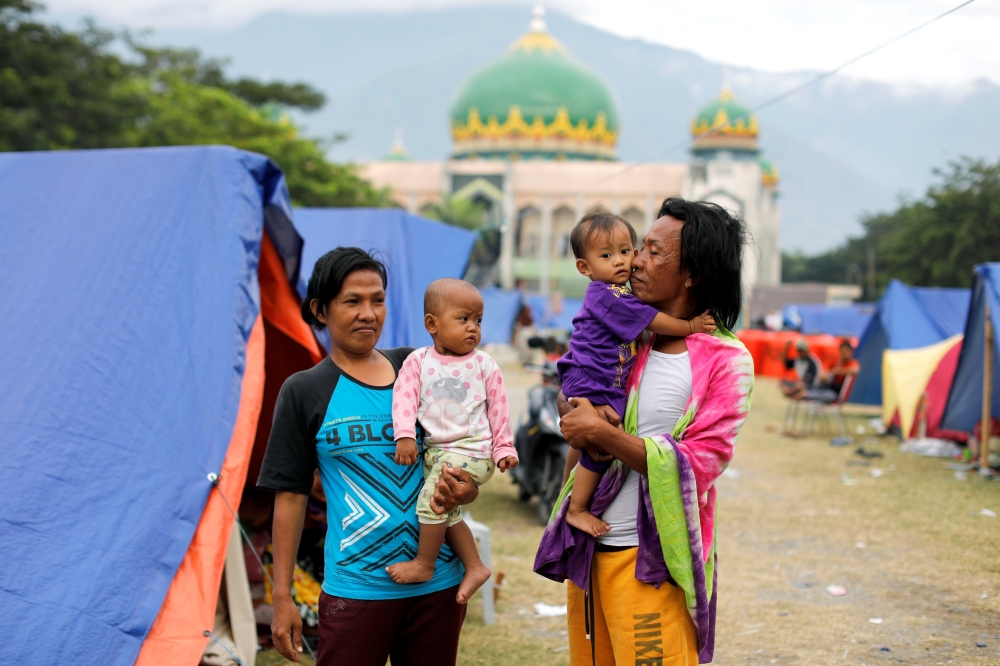 A family is seen outside their tent at a camp for displaced victims of the earthquake and tsunami in Palu, Central Sulawesi, Indonesia, October 9, 2018. REUTERS/Jorge Silva