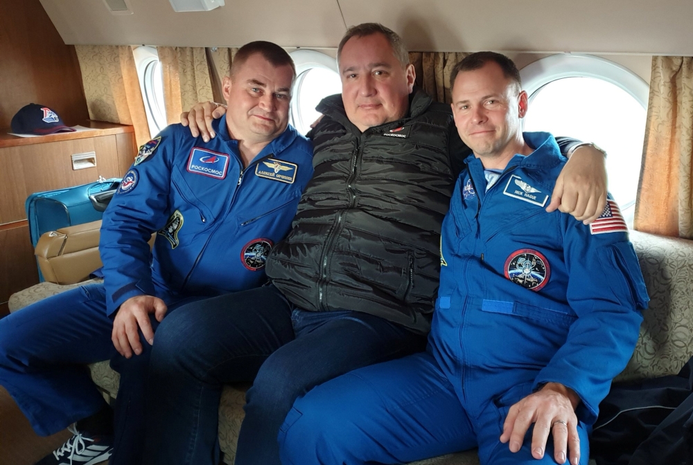 Head of Russian space agency Roscosmos Dmitry Rogozin (C) poses with astronauts Alexey Ovchinin of Russia and Nick Hague of the U.S., who survived the mid-air failure of a Russian rocket, on onboard a plane during a flight to Chkalovsky airport near Star 