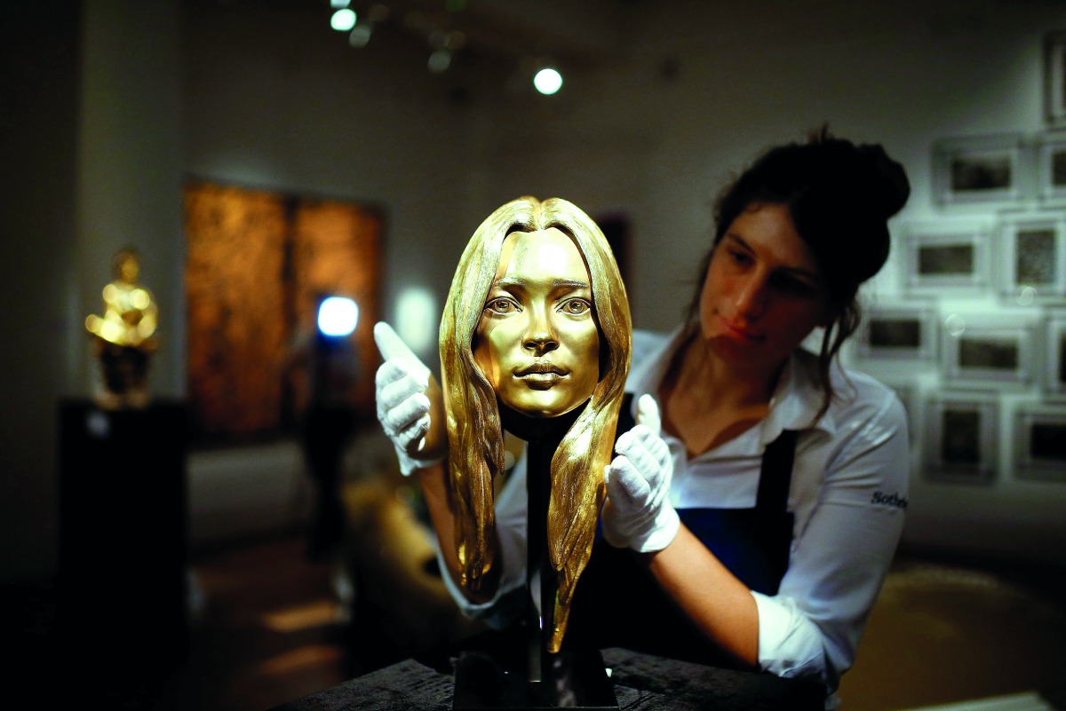 A Sotheby's employee poses with a bust of Kate Moss in solid 18-carat gold during a photocall for 'The Midas Touch' collection at Sotheby's in London, Britain, October 12, 2018. Reuters/Henry Nicholls