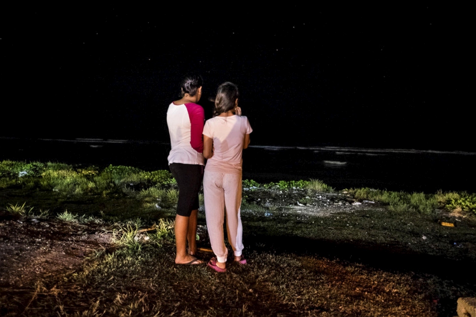 Two asylum-seekers look at the ocean in front of the community-based camp for families with children on the island of Nauru, October 2014.  © UNHCR/Vlad Sokhin