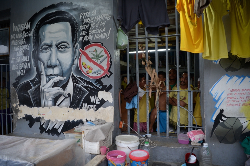 This photo taken on August 13, 2018, inmates standing next to a portrait of Philippine President Rodrigo Duterte inside the city jail in Manila. AFP / TED ALJIBE 