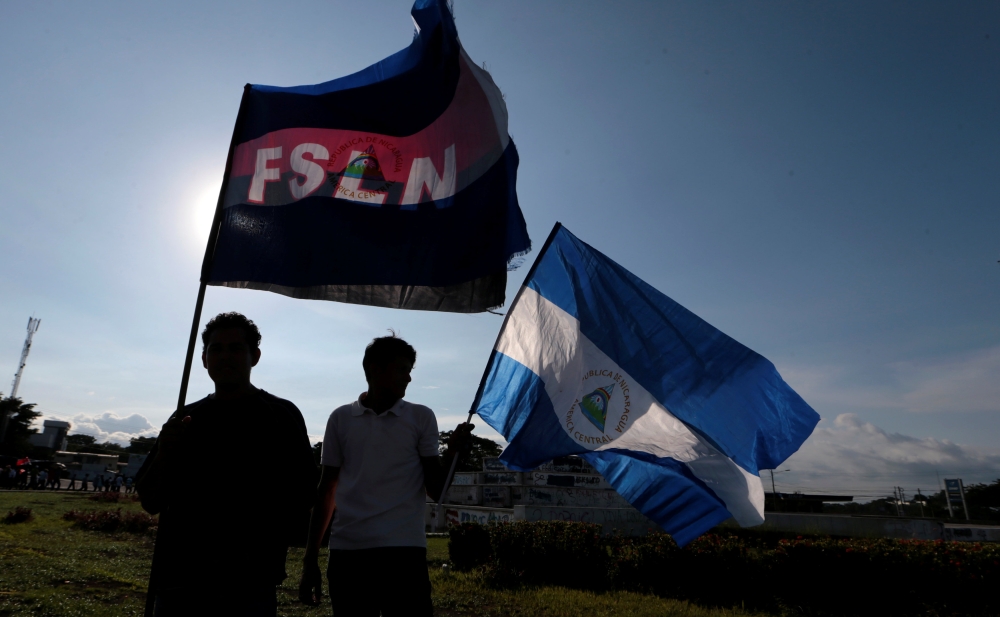 Supporters of Nicaraguan President Daniel Ortega hold flags of Nicaragua and the Sandinista party during a march called 