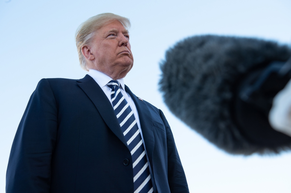 Following a campaign rally, US President Donald Trump speaks to reporters before boarding Air Force One at Elko Regional Airport in Elko, Nevada, on October 20, 2018. / AFP / NICHOLAS KAMM