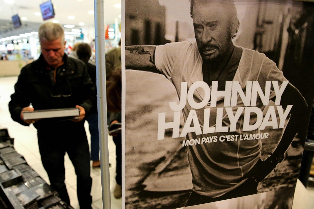 A fan of the late French singer Johnny Hallyday looks at Johnny Hallyday merchandising items, on the day of the release of his posthumous album 