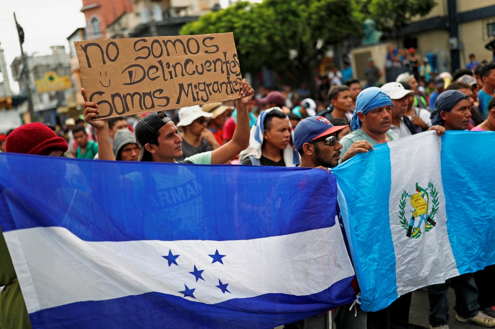 Central Americans, part of a caravan trying to reach the U.S., protest by the border gate as they wait to cross into Mexico and carry on their journey, in Tecun Uman, Guatemala, October 28, 2018. The placard reads 