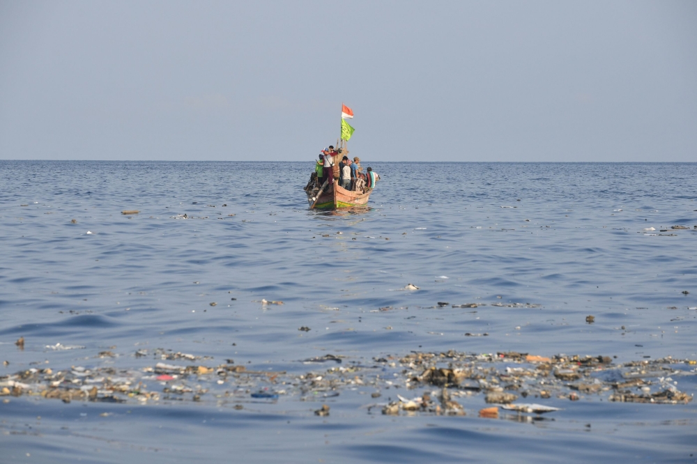 A boat sails in the background as debris from the ill-fated Lion Air flight JT 610 floats at sea in the waters north of Karawang, West Java province, on October 29, 2018.   AFP / ADEK BERRY

