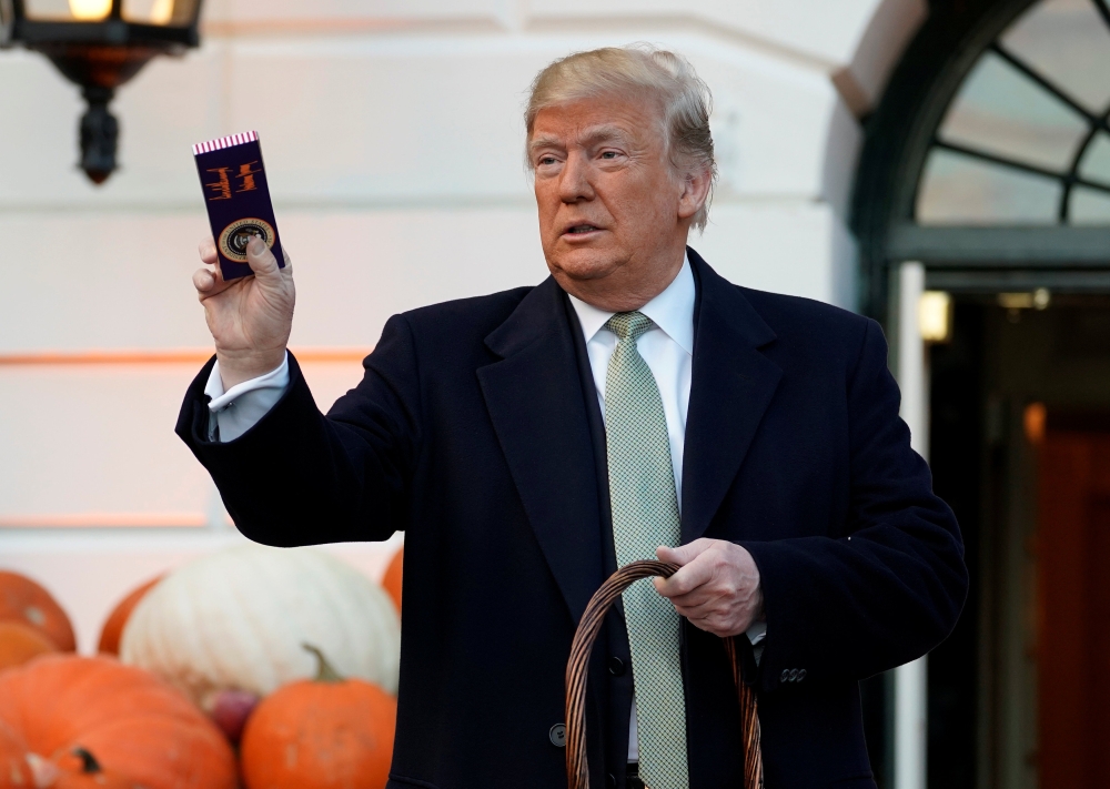 US President Donald Trump holds up a Halloween candy with his signature on it before giving it to trick-or-treaters at the White House in Washington, U.S., October 28, 2018. REUTERS/Joshua Roberts
 