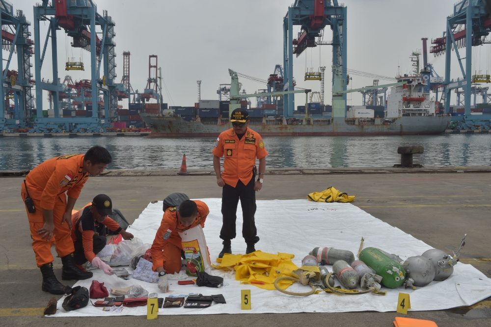 Indonesian SAR members display personal items of passengers of the ill-fated Lion Air flight JT 610 at the Jakarta port on October 30, 2018. / AFP / ADEK BERRY 