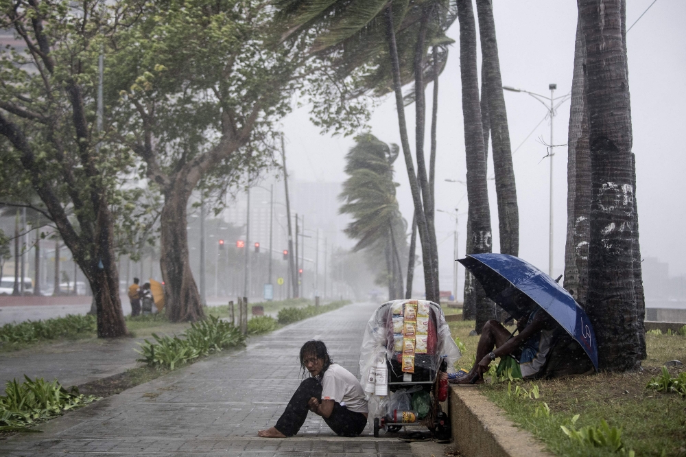  Streetside vendor shivers in the rain as weather patterns from Typhoon Yutu affect Manila Bay on October 30, 2018. AFP / NOEL CELIS
