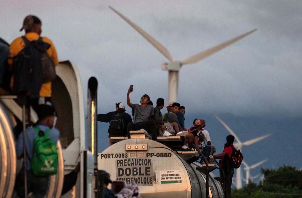 A truck carrying mostly Honduran migrants taking part in a caravan heading to the US, passes by a wind farm on their way from Santiago Niltepec to Juchitan, near the town of La Blanca in Oaxaca State, Mexico, on October 30, 2018. AFP / GUILLERMO ARIAS
