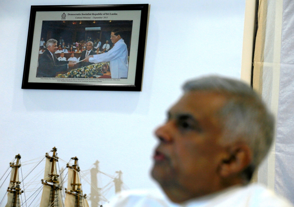 A photograph of Sri Lanka's ousted Prime Minister Ranil Wickremesinghe taking an oath as he was sworn in before President Maithripala Sirisena in 2015, is seen on a wall as Wickremesinghe speaks during an interview with Reuters at the Prime Minister's off