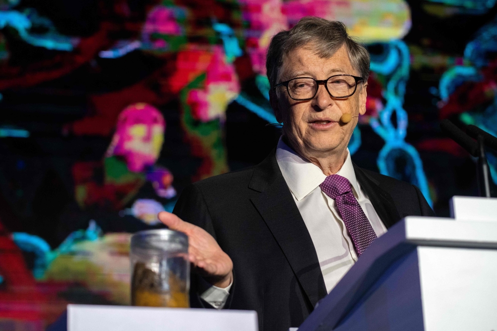 Microsoft founder Bill Gates (R) talks next to a container (L) with human feces during the 