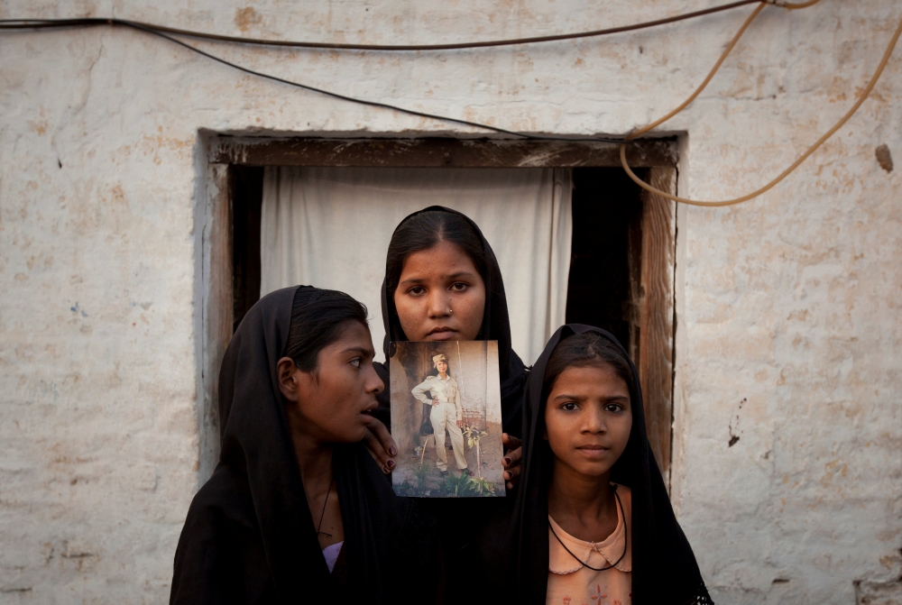 The daughters of Pakistani Christian woman Asia Bibi pose with an image of their mother while standing outside their residence in Sheikhupura located in Pakistan's Punjab Province November 13, 2010.  Reuters/Adrees Latif