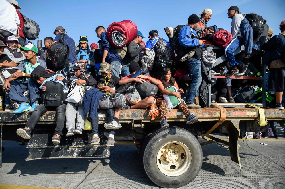 Central American migrants -mostly honduran- taking part in a caravan to the US, get on a truck heading to Irapuato in the state of Guanajuato on November 11, 2018 after spending the night in Queretaro in central Mexico.  AFP / Alfredo Estrella 