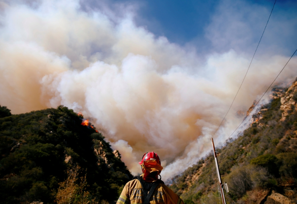 Firefighters battle the Woolsey Fire as it continues to burn in Malibu, California, U.S., November 11, 2018. Reuters/Eric Thayer