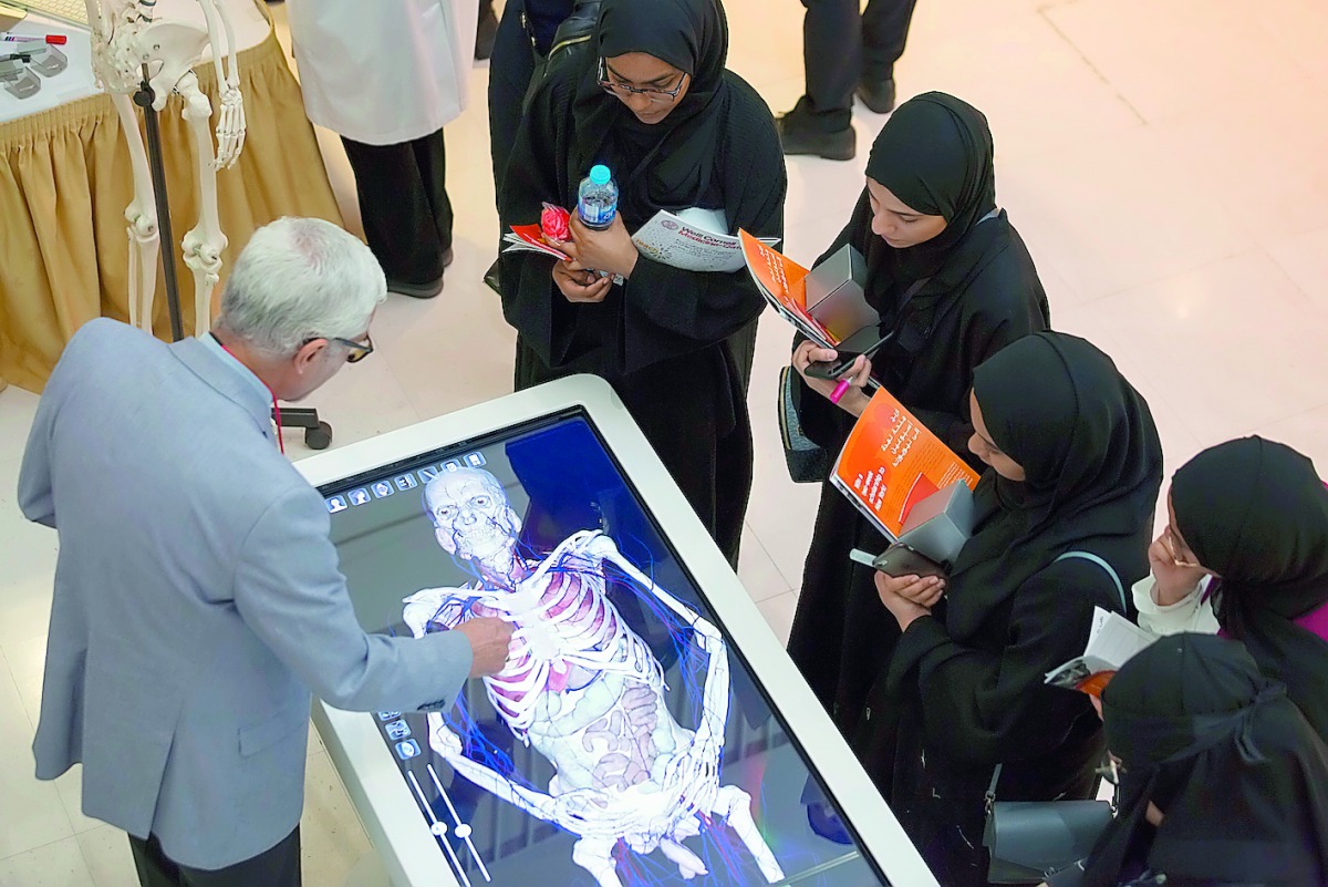 A staff of WCM-Q explains to students about various parts of human body at an anatomage table during the event. 