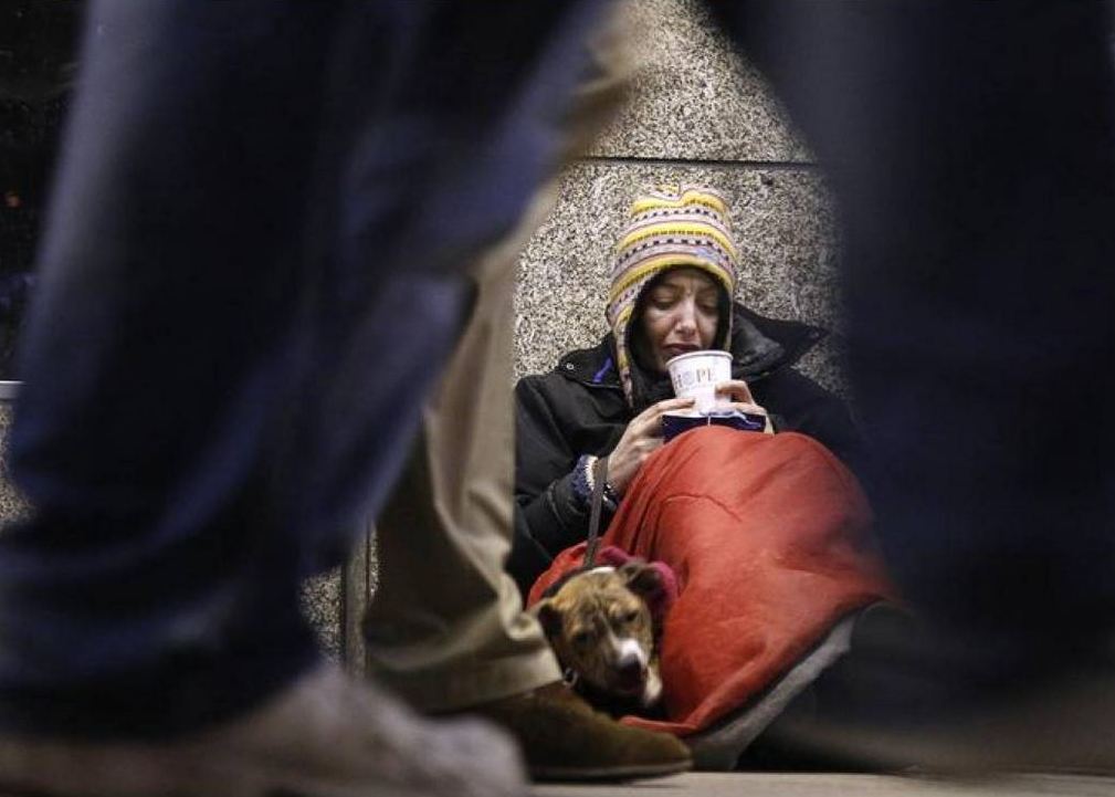 A homeless woman from north Wales sits huddled under a sleeping bag next to her dog Casper in a shopping arcade near the Victoria rail station in London, December 14, 2012. Reuters/Chris Helgren