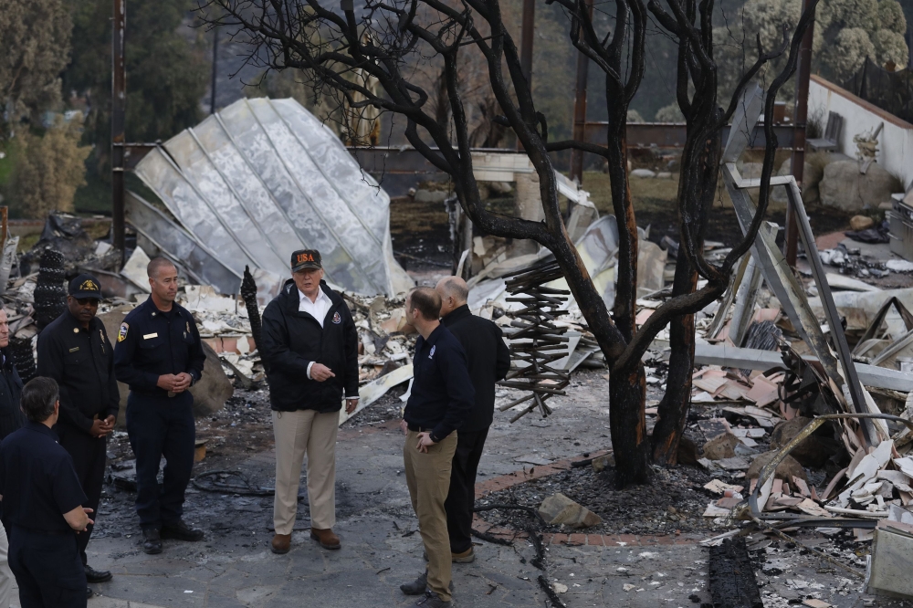 President Donald Trump (C) surveys the damage from the Woolsey fire in Malibu on November 17, 2018. / AFP / POOL / Genaro Molina
