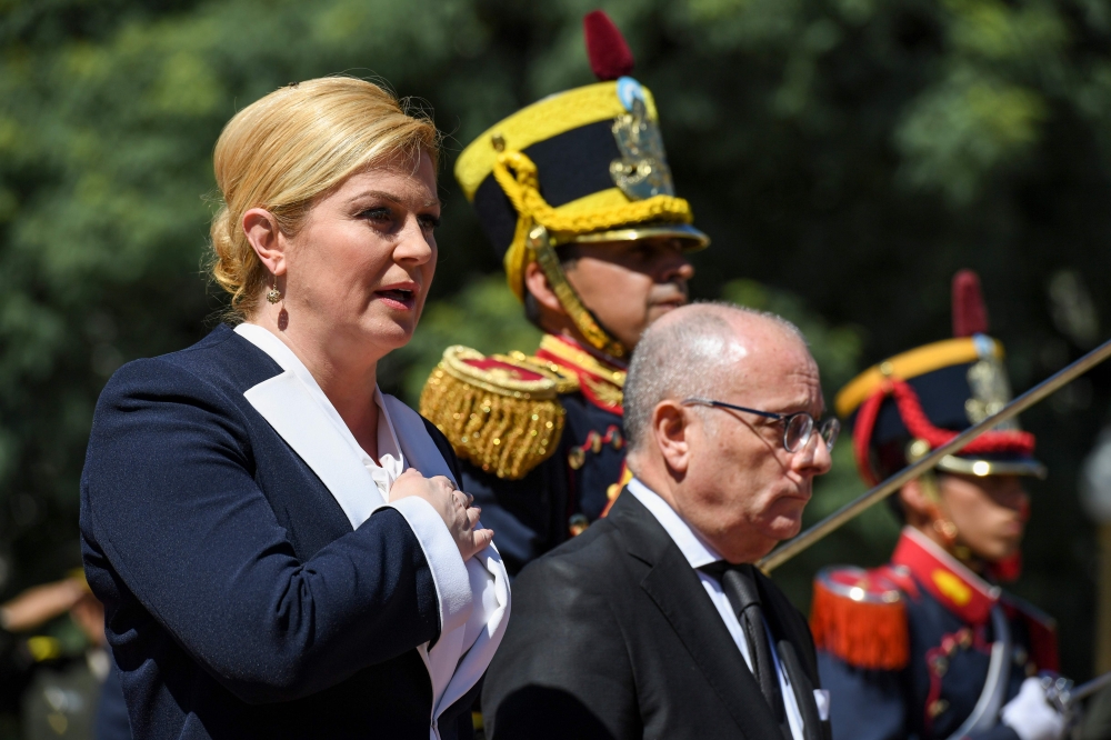 FILE PHOTO: President Kolinda Grabar-Kitarovic sings Croatia national anthem next to Argentine FM Jorge Faurie, during a wreath-laying ceremony to pay homage to Jose de San Martin in Buenos Aires. AFP/Eitan Abramovich