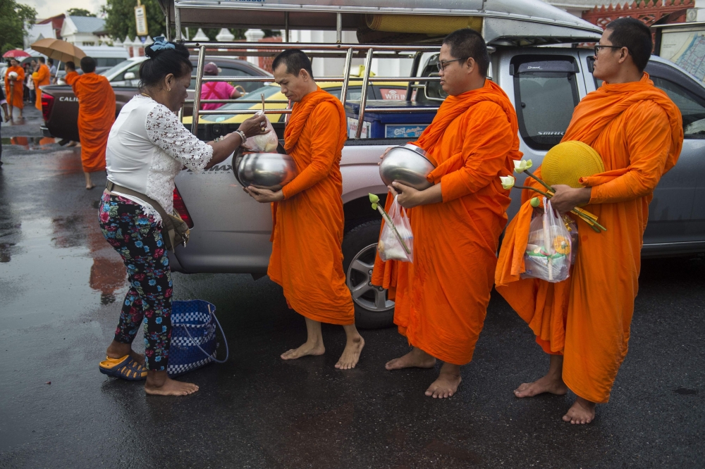 This picture taken on October 23, 2018, shows a devotee giving food offerings to Buddhist monks outside a temple in Bangkok. Romeo Gacad / AFP