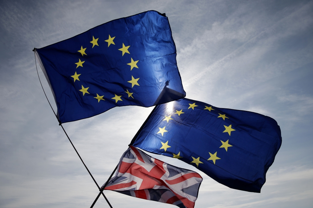 FILE PHOTO: In this file photo taken on September 24, 2017 European and Union flags flutter in the breeze on the seafront in Brighton, during a march against Brexit. AFP / Daniel LEAL-OLIVAS
