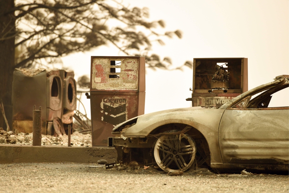 In this file photo taken on November 11, 2018 a burnt car and a gas station remain visible after the 