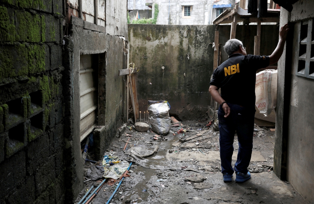 A member of the Philippine National Bureau of Investigation inspects the site where Kian Lloyd delos Santos, a 17-year-old student, was killed during anti-drug operations in Caloocan, Metro Manila, Philippines August 23, 2017. Reuters/Erik De Castro