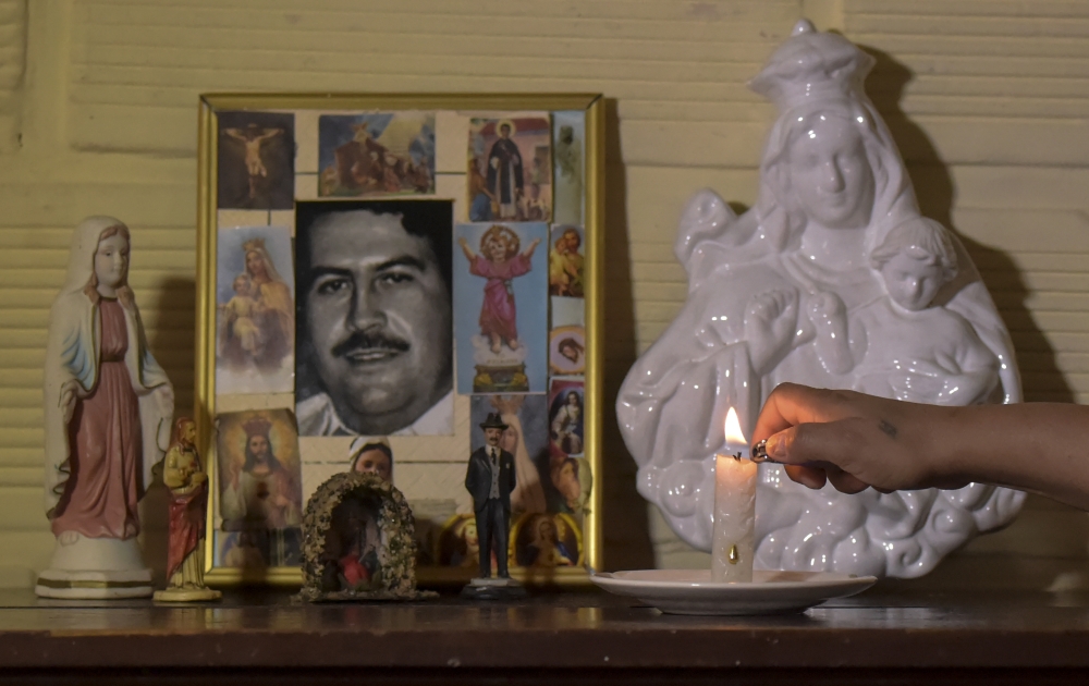 Maria Eugenia Castano, resident of Pablo Escobar neighborhood, lights a candle at the portrait of Colombian drug lord Pablo Escobar in her house on November 28, 2018, in Medellin, Colombia. / AFP / Raul ARBOLEDA 
