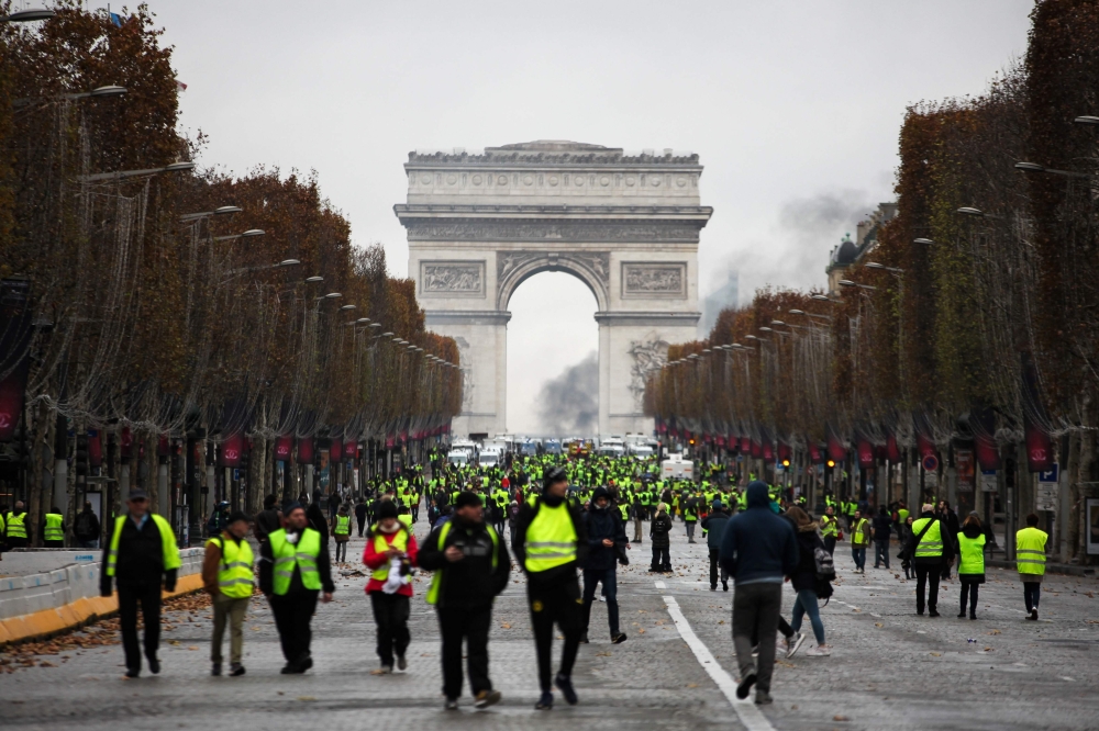 Demonstrators walk near the Arc de Triomphe during a protest of Yellow vests (Gilets jaunes) against rising oil prices and living costs, on December 1, 2018 in Paris.  AFP 
