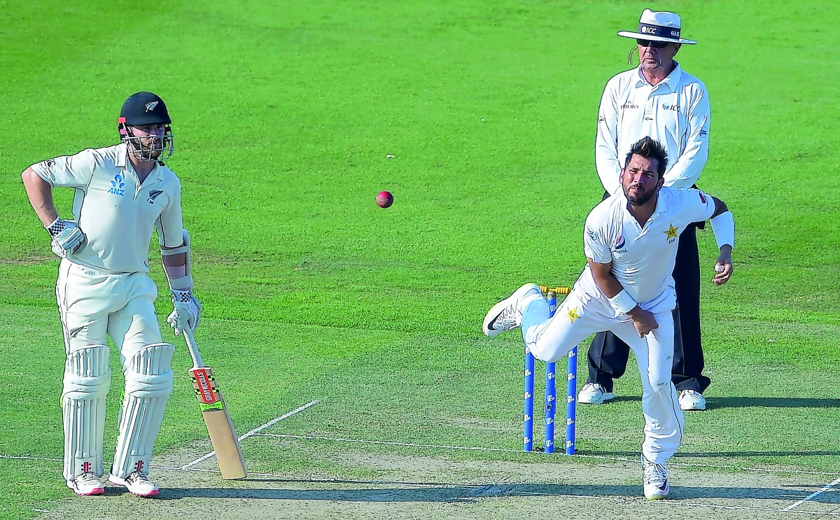 Pakistani spinner Yasir Shah (R) delivers the ball as New Zealand captain Kane Williamson (L) looks on during the first day of the third and final Test cricket match between Pakistan and New Zealand at the Sheikh Zayed International Cricket Stadium in Abu