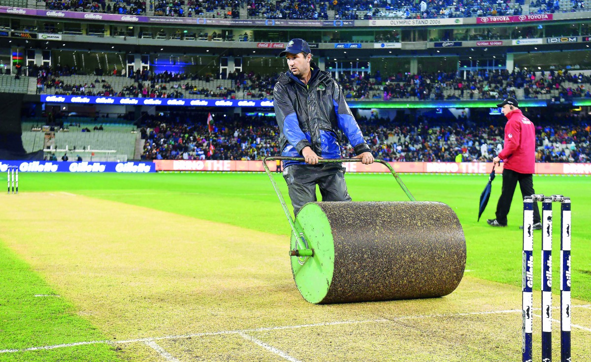 A photo taken on November 23, 2018 shows Melbourne Cricket Ground (MCG) curator Matt Page (L) rolling the pitch during the innings break of the Australia versus India T20 international cricket match in Melbourne.  AFP / William West

