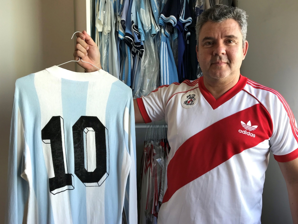 River Plate fanatic Javier Maluf poses with the jersey of Argentine striker Diego Maradona from the World Cup 1980 match between Argentina and England at his home in the Qatari capital, Doha on December 8, 2018. / AFP / FETHI BELAID 