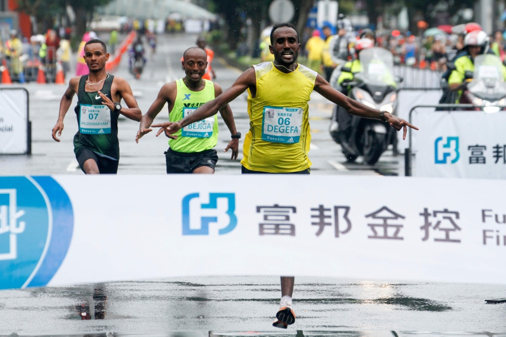 Kenya's Aredom Tiumay Degefa celebrates before crossing the finish line to win the men's race of the Taipei marathon on December 9, 2018. AFP / HSU Tsun-hsu 