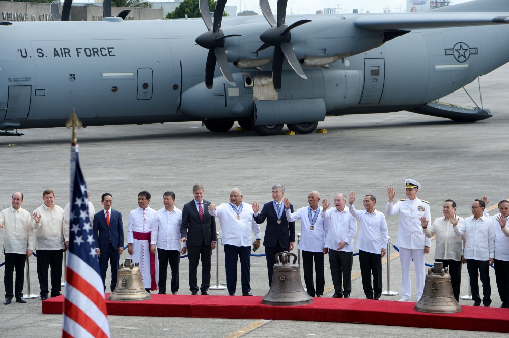 Philippine and US officials, including representatives from the Catholic church, pose for photos next to three Balangiga church bells shortly after they arrived from the US at a military airbase in Manila on December 11, 2018.  / AFP / Ted ALJIBE 
