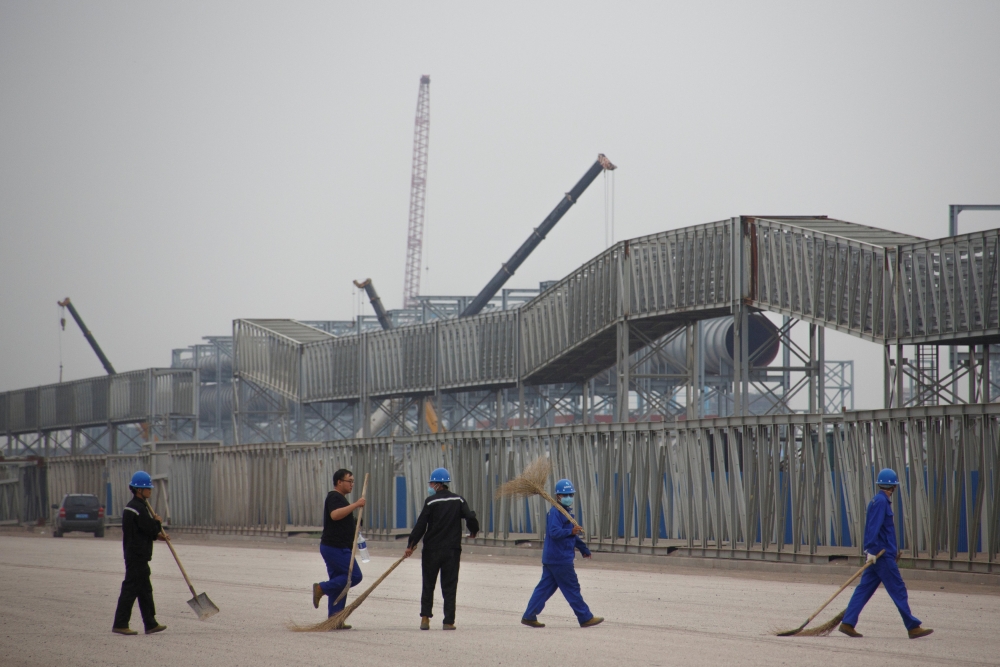 File photo: Workers walk in front of the Hebei Zongheng Iron and Steel plant that is under construction at the Tangshan Fengnan Economic Development Zone, Hebei province, China, August 22, 2018. REUTERS/Thomas Peter/File Photo