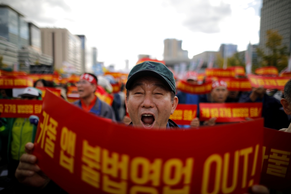 FILE PHOTO: A taxi driver takes part in a protest against a carpool service application that will be launched by Kakao Corp later this year, in central Seoul, South Korea, October 18, 2018. The banners read, 