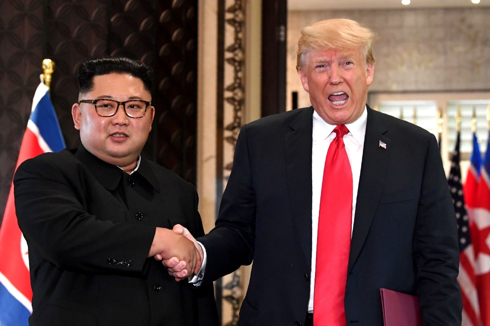 (FILES) In this file photo taken on June 12, 2018, US President Donald Trump (R) and North Korea's leader Kim Jong Un shake hands following a signing ceremony during their historic US-North Korea summit, at the Capella Hotel on Sentosa island in Singapore