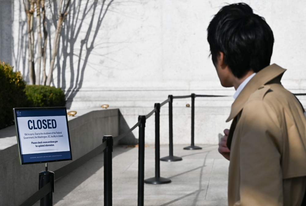 A man reads a sign displayed on a government building that is closed because of a US government shutdown in Washington, DC, on December 22, 2018. / AFP / ANDREW CABALLERO-REYNOLDS 