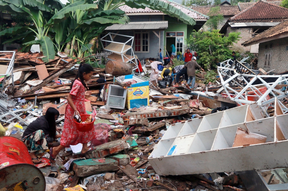 Children, who affected by the tsunami at Sunda Strait, collect snacks from a collapsed shop at Rajabasa in South Lampung, Indonesia, December 25, 2018. REUTERS/Stringer 