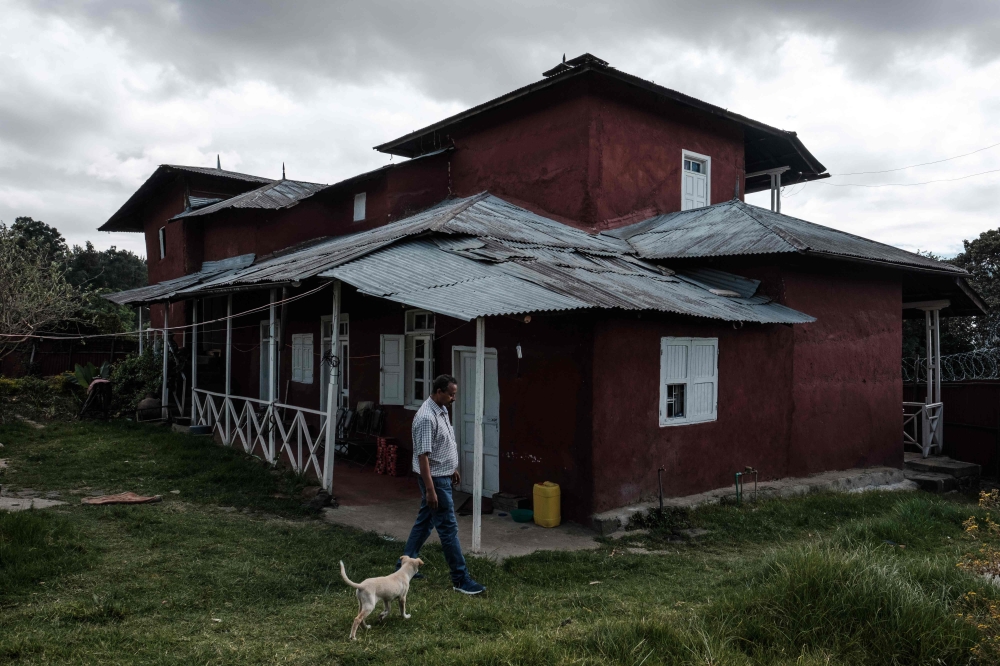 Berhanu Mengistuin walks his dog in front of his family house which has been protected as a historic house by the tourism bureau in Addis Ababa, on November 29, 2018. AFP / EDUARDO SOTERAS