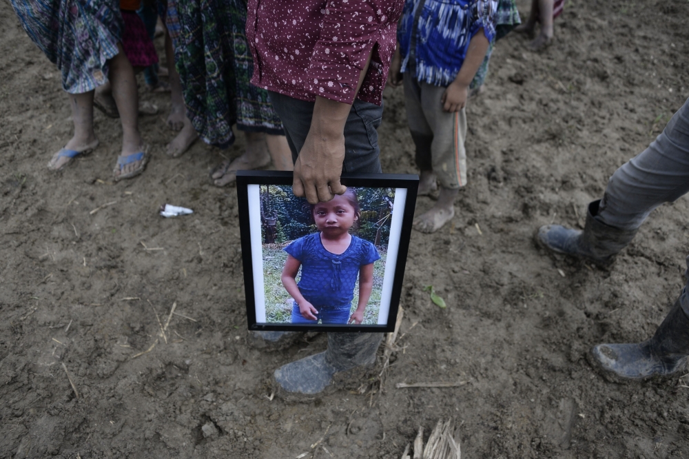 A person holds a picture of seven-year-old Jakelin Caal, who died in a Texas hospital two days after being taken into custody by US border patrol agents in a remote stretch of the New Mexico desert, during her funeral in the village of San Antonio Secorte