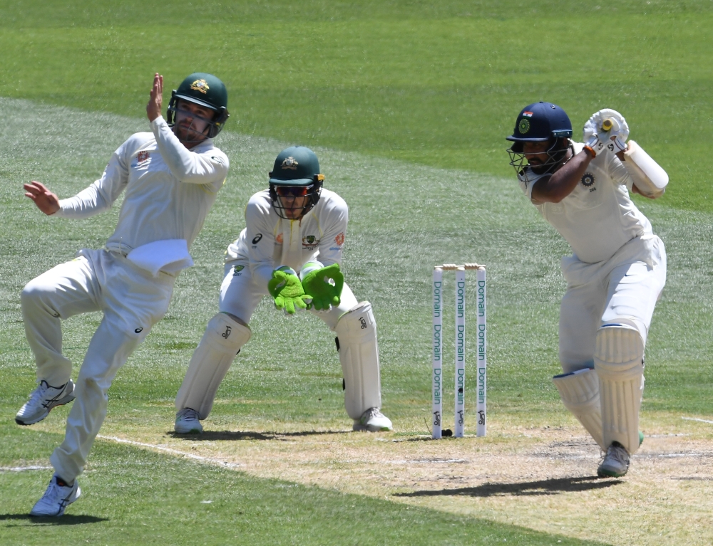 India's Cheteshwar Pujara (R) plays a shot as Australia's Travis Head (L) and captain Tim Paine field on day two of the third test match between Australia and India at the MCG in Melbourne, Australia, December 27, 2018. (AAP/Julian Smith via REUTERS)