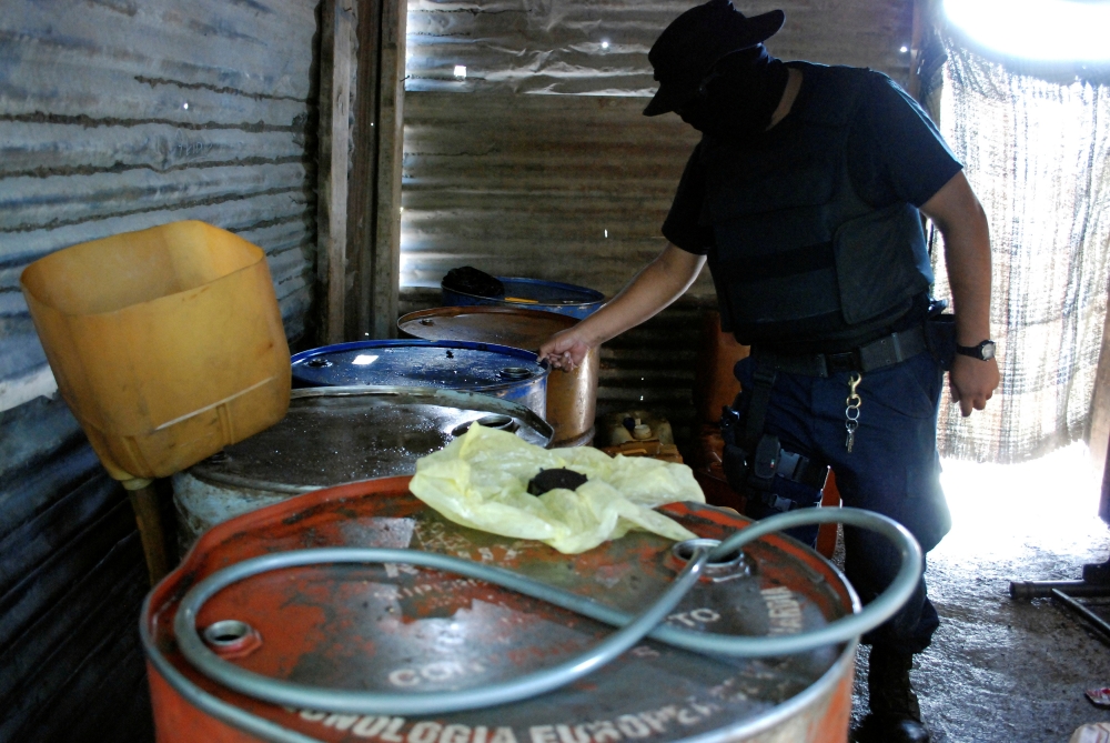 FILE PHOTO: A policeman inspects barrels containing stolen diesel fuel, stored in a tire repair shop, during an operation in the municipality of Apodaca, neighboring Monterrey July 4, 2011. Picture taken July 4, 2011. REUTERS/Josue Gonzalez/File Photo
