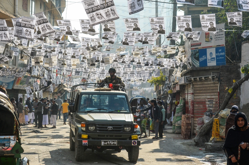 Bangladeshi army personnel drive a military vehicle through a street adorned with election posters near a polling station in Dhaka on December 30, 2018. AFP / Munir UZ ZAMAN