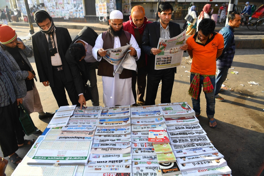 Bangladeshi people read newspapers carrying headlines of the general election results in Dhaka on December 31, 2018.  AFP / Indranil MUKHERJEE
