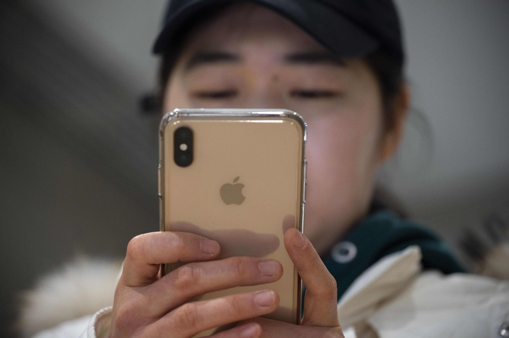 A woman uses an Apple iPhone at a shopping mall in Beijing on January 3, 2019. Apple cut its revenue outlook for the latest quarter on January 3, citing steeper-than-expected 