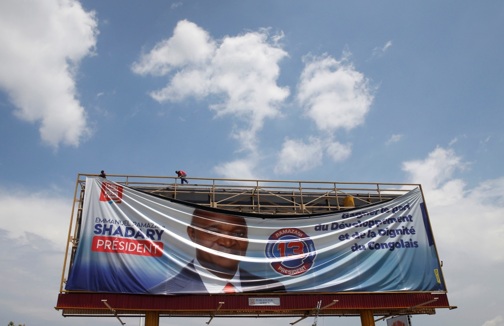 Men remove an electoral campaign banner of Emmanuel Ramazani Shadary, former Congolese Interior Minister and presidential candidate in Kinshasa, Democratic Republic of Congo, January 2, 2019. REUTERS/Baz Ratner
